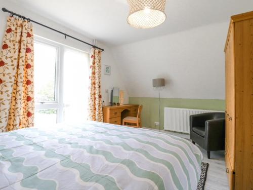 a bedroom with a bed and a chair and a window at Kingfisher in Ely