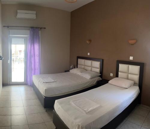 a bedroom with two beds and a door with a window at House Filippos in Sarti