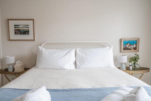 a white bed with white pillows and two night stands at The Beach House in Melcombe Regis