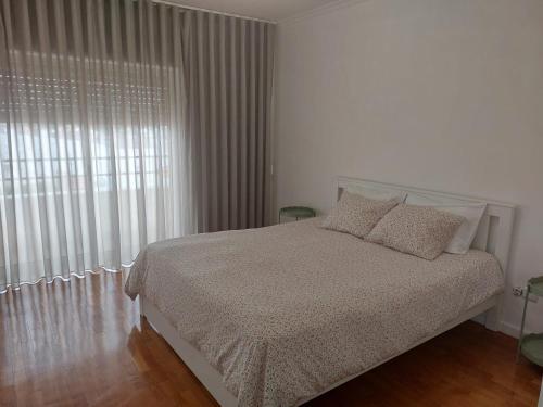 a white bedroom with a bed and a window at apartamento Bitarães Paredes in Bitarães