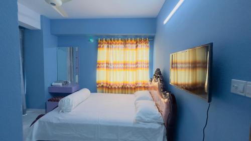 a blue room with a bed and a window at Baridhara Sweet Home in Dhaka