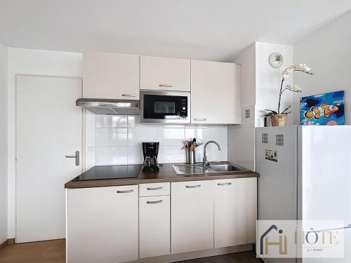 La cuisine blanche est équipée d'un évier et d'un réfrigérateur. dans l'établissement L'Écume Douce - Sea View & Charm, à Bray-Dunes