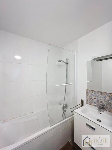 une salle de bain blanche avec une douche et un lavabo dans l'établissement L'Écume Douce - Sea View & Charm, à Bray-Dunes