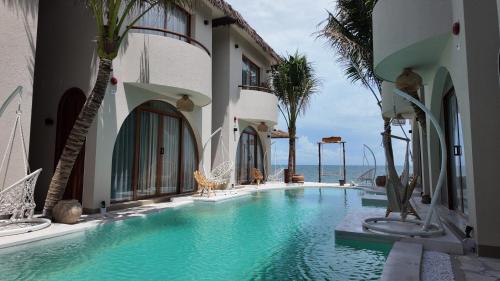 a swimming pool with palm trees next to a building at La Mer Bali Mui Ne in Phan Thiet