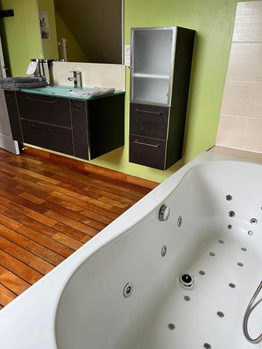 La salle de bains est pourvue d'une baignoire blanche et d'un lavabo. dans l'établissement Albizia, à Sainte-Geneviève