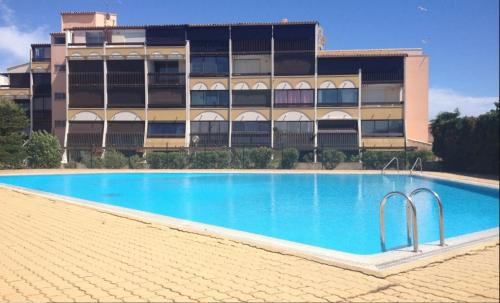 une grande piscine devant un immeuble dans l'établissement Studio Village Naturiste Port Venus Sensation, au Cap d'Agde