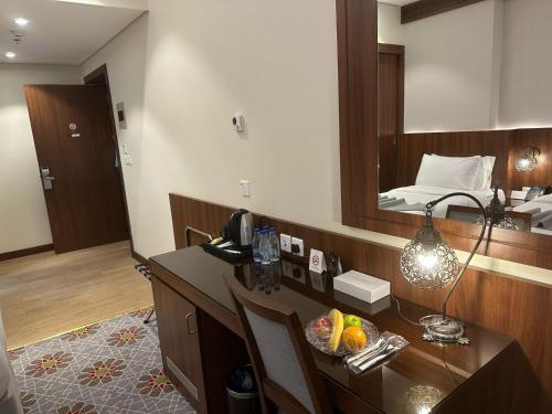 a room with a desk with a mirror and a bed at Maysan Rehab Al Mysk Hotel in Al Madinah