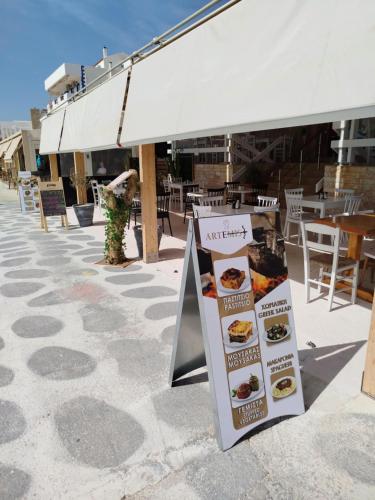 a sign on a sidewalk in front of a restaurant at ARTEMIS beach studios in Kalamaki Heraklion