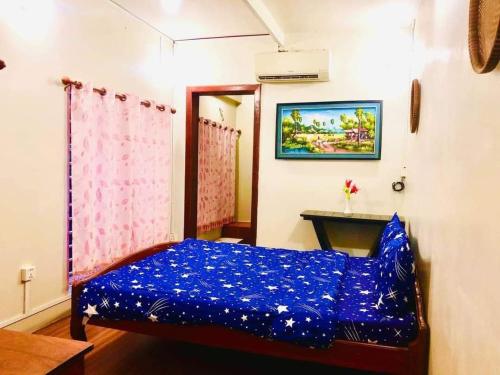 a bedroom with a blue bed and a table at Sihariddh Guesthouse in Siem Reap