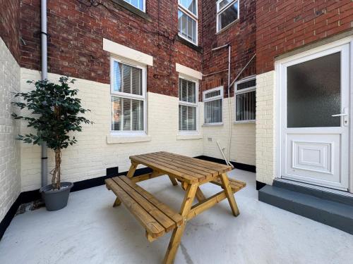 a wooden picnic table in front of a building at Belford Apartment 1, Close to Tynemouth in Tynemouth