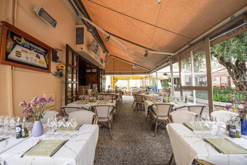 un restaurant avec des tables et des chaises blanches et des fenêtres dans l'établissement Le 3 Pièces de la Vieille Ville, à Menton