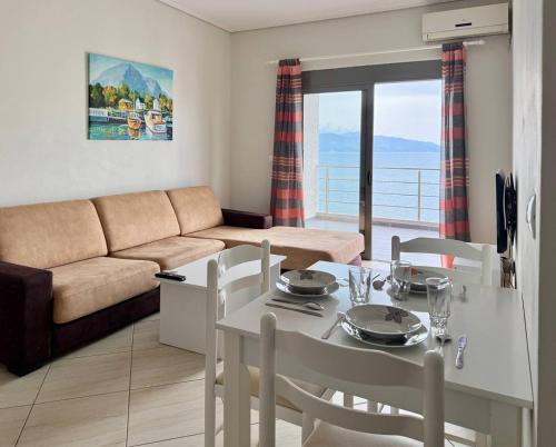una sala de estar con una mesa, sillas y un sofá en Plutus Sea View Apartment, en Sarandë