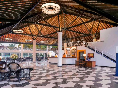 a lobby with chairs and tables in a building at Novotel Goa Dona Sylvia Resort in Cavelossim