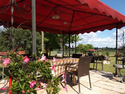 a table and chairs under a red umbrella at Gedeon Tanya Panzió in Jakabszállás