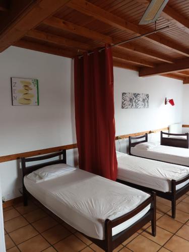 - 2 lits dans une chambre avec rideau rouge dans l'établissement Refuge d'étape Zuharpeta Randonneur Pèlerin, à Saint-Jean-Pied-de-Port