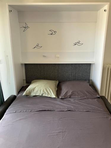 un lit avec trois oiseaux sur le mur au-dessus dans l'établissement Charmant studio Avignon intra-muros, à Avignon