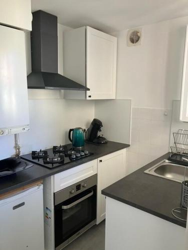 une cuisine avec des armoires blanches et un four à plaques de cuisson dans l'établissement Charmant studio Avignon intra-muros, à Avignon