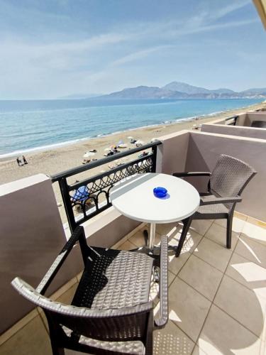 a table and chairs on a balcony with the beach at ARTEMIS beach studios in Kalamaki Heraklion