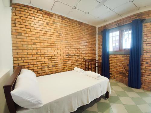 ein Schlafzimmer mit einem weißen Bett in einer Ziegelwand in der Unterkunft Chandra Holiday Home in Dikwella