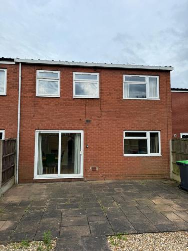 a red brick house with white windows and a patio at Quiet, Sleeps 12, 2 bathrooms, Lots of parking, KIA 2 in Nottingham