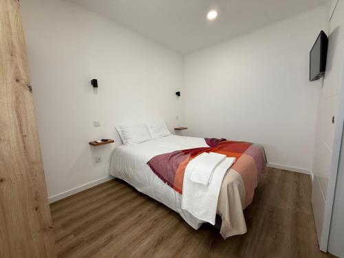 a bedroom with a bed in a white room at 5Melros in Santiago do Cacém