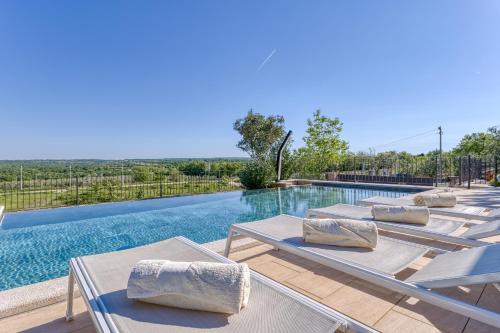 a row of chaise lounge chairs next to a swimming pool at Villa Sana in Selina