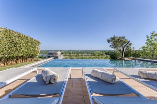 a pool with two blue chaise lounges next to a swimming pool at Villa Sana in Selina