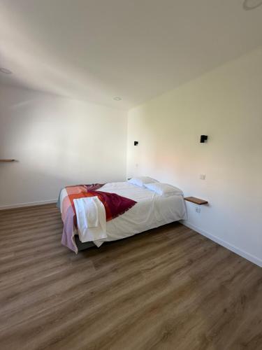 a bed in a white room with a wooden floor at 5Melros in Santiago do Cacém