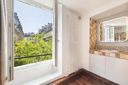 La salle de bains est pourvue d'une fenêtre et d'un lavabo. dans l'établissement Ecarlate, à Paris