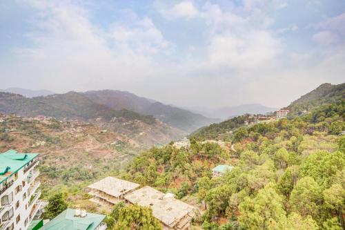 a view of a mountain with buildings and trees at Alaya Stays Serene Woods Retreat With Lift & Restaurant Amid Nature in Dharampur