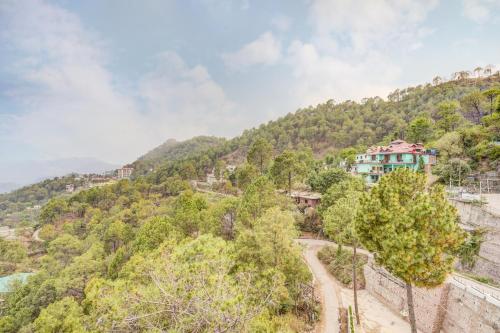a house on top of a hill with trees at Alaya Stays Serene Woods Retreat With Lift & Restaurant Amid Nature in Dharampur