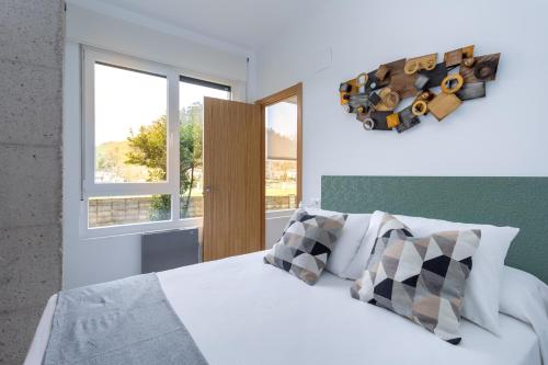 a bedroom with a white bed and two windows at Apartamentos Liérganes Centro in Liérganes