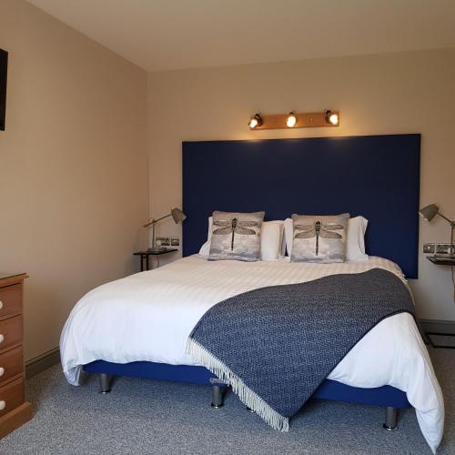 a bedroom with a large bed with a blue headboard at Acorn Cottage in Boston