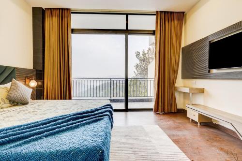 a bedroom with a bed and a flat screen tv at Alaya Stays Serene Woods Retreat With Lift & Restaurant Amid Nature in Dharampur
