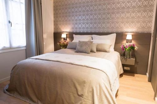 a bedroom with a large bed with two lamps and flowers at Hôtel Roi de Sicile - Rivoli in Paris