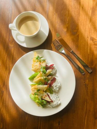 a white plate with a sandwich and a cup of coffee at Hotel Vento in Ventspils