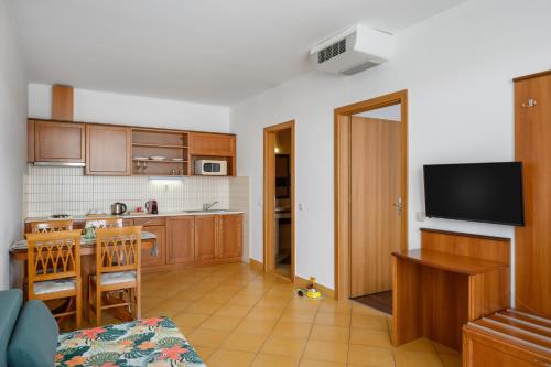 a kitchen with wooden cabinets and a table and a television at Thermal Park Hotel Egerszalók in Egerszalók