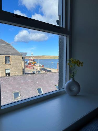 a window with a vase sitting on a window sill at 2 Peterson closs in Lerwick
