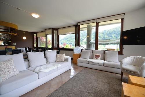 a living room with two white couches and windows at Hotel Sorriso in Ponte di Legno