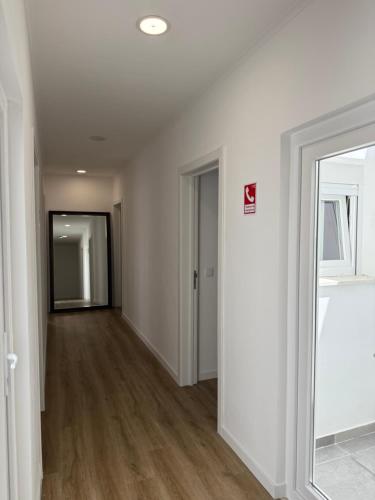 an empty hallway with white walls and wood floors at 5Melros in Santiago do Cacém