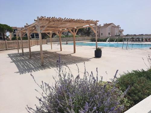 une piscine avec une pergola en bois et une piscine dans l'établissement Ecrin du Sud, au Barcarès