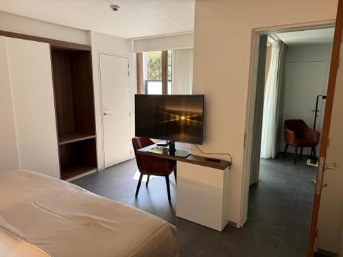 a bedroom with a bed and a desk with a television at Casino Hotel in Koksijde