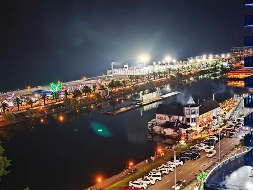 a city at night with cars parked next to a river at Апартаменты Батуми первая линия in Batumi
