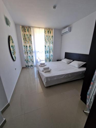 a bedroom with a white bed and a window at Апартамент БАНГЕВИ in Burgas