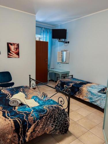 a bedroom with two beds and a tv on the wall at La Locanda Del Brolio in Cantiano