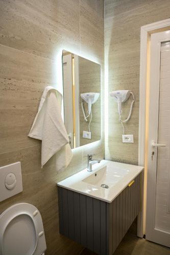 a bathroom with a sink and a toilet and a mirror at Swiss Lux apartments in Durrës