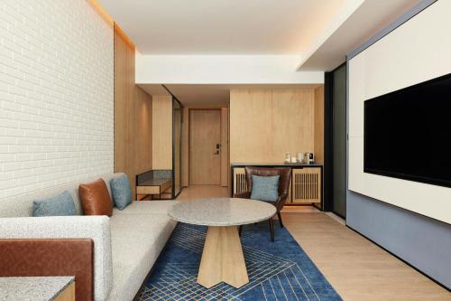a living room with a table and a tv at Four Points by Sheraton Shanghai International Tourism and Resorts Zone in Nanhui