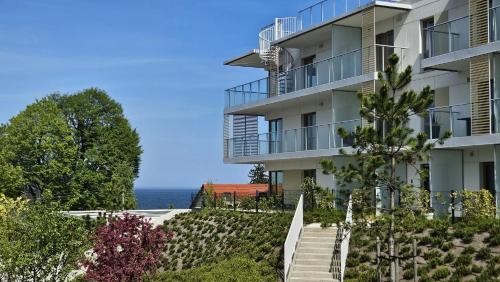 an apartment building with stairs and the ocean in the background at Mechelinki, Apartament z ogródkiem, widokiem na morze i aneksem kuchennym in Mechelinki
