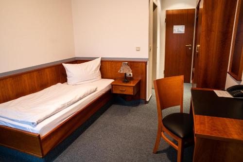 a bedroom with a bed with a desk and a chair at Hotel-Restaurant Thomsen in Delmenhorst