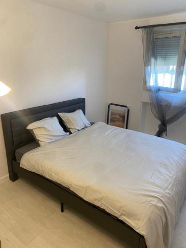 - une chambre dotée d'un grand lit avec des draps blancs et une fenêtre dans l'établissement T2 Charenton Proche Paris Bercy, à Charenton-le-Pont